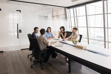 Beş çok ırklı profesyonel brifinge katılıyor, proje güncellemelerini tartışıyor, fikirleri paylaşıyor, çözümleri tartışıyor, plan stratejilerini tartışıyor, modern konferans odasında kurumsal eğitim alıyor