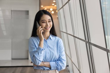 Çinli iş kadını müşterisiyle cep telefonuyla resmi bir konuşma yaptı, gülümsedi, proje detaylarını tartıştı, toplantı planladı, geri bildirim ya da telefonla profesyonel yardım sağladı.