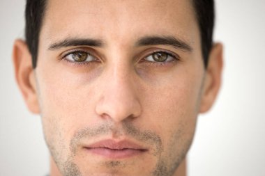 Doğal erkeksi güzellik. Kırpılmış portreyi kapat yakışıklı genç erkek yüzü kahverengi gözlü şık sakallı sakin bir ifadeyle kameraya bakıyor. Yüz bakımı öz güven kavramı