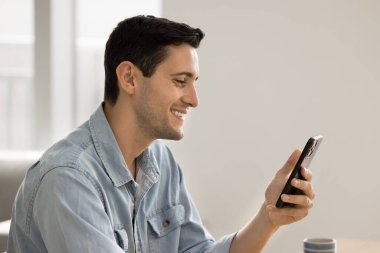 Akıllı telefon nişanı. Yan görünüm mutlu gen z adam modern cep telefonu tutun sosyal ağ hesabında mesaj metni okuma keyfini kayan web sayfaları arkadaşı ile çevrimiçi iletişim