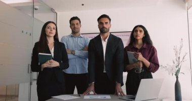 Çok ırklı, farklı etnik çeşitlilikte iş dünyası pazarlama ekibi ve ofis yönetim kurulunda portre için bekleyen genç bayan lider, kameraya bakıyor, gülümsüyor, gülüyor, birlikte poz veriyorlar.