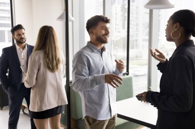 Fikir alışverişi. Çeşitli iş adamları farklı etnik kökenlere sahip çalışma arkadaşları modern ofiste çift olarak duruyorlar ya da ortak çalışma alanı sohbetleri sırasında evrak işlerini tartışıyorlar.