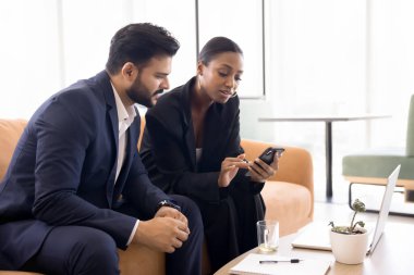 Danışmanlık hizmeti ve teknoloji. Akıllı kadın emlakçı cep telefonu ekranında genç iş adamına dijital belge sunumu gösteriyor. Uygulama kullanarak vergi oranı hesaplamaları yapıyor. Boşluğu kopyala