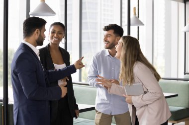 İş yerinde sıcak ilişkiler. Dost canlısı uluslararası takım 4 çalışanı ara zamanı bir araya gelip sohbet ediyorlar. Birlikte çalışma ofisinde eğleniyorlar. Resmi olmayan iletişimin tadını çıkarıyorlar.