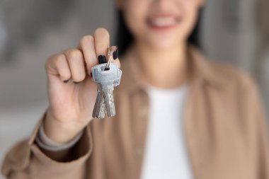 Kapalı, gülümseyen kadın ev anahtarlarını tutuyor, ilk ev ya da mülk alımının sembolü olarak, yeni başlangıçlar, ev sahipliği, gayrimenkul başarısı, bir hedefe ulaşmak, yeni bir eve taşınmak