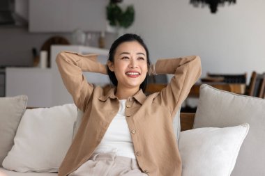 Mutlu, 30 'lu yaşlardaki Asyalı genç bir kadın kanepeye yaslanmış, beyaz yumuşak yastıklara yaslanmış, kollarını başının arkasına uzatmış, rahatlamış ya da stressiz hissediyordu, evinde rahat bir anın tadını çıkarıyordu. Rahatlatıcı, hobi