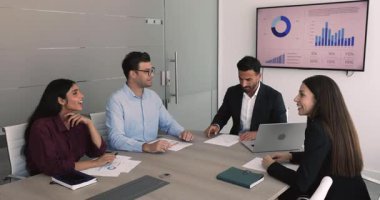 Geniş ofis masasında toplanan, yönetim kurulunda konuşan, gülen, takım çalışması için fikir üreten yaratıcı strateji planlayan, iş birliğini tartışan çeşitli genç profesyonel takımlar.