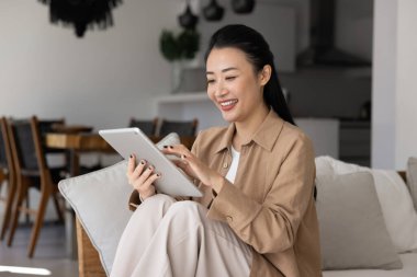 Mutlu kadın evde modern tablet kullanımından hoşlanıyor, sosyal medya üzerinden arkadaşıyla sohbet ediyor, pazar uygulaması veya platform üzerinden iyi ve elektronik hizmetler satın alıyor, uzaktan dijital iletişimi yönetiyor