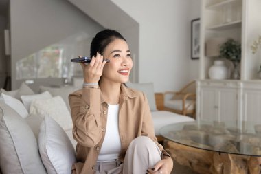 Kadın rahat bir kanepeye oturur, akıllı telefonu kulağının dibinde tutar, sesli mesaj dinler, hoparlörden kişisel sohbetin tadını çıkarır. Sesli mesaj paylaşımı, uzaktan iletişim, modern teknoloji kolaylıkla kullanım