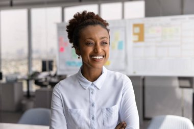 Gülümseyen Afrikalı iş kadınının portresi, yönetici müdür veya CEO 'nun toplantı odasında kolları bağlı poz vermesi, neşeli bir ifadeyle mesafeye bakması, liderlik ve güven yayıyor.