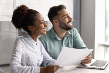 İki takım arkadaşı dizüstü bilgisayar ve kağıtlarla birlikte oturup mutlu bir gülümsemeyle mesafeye bakıyorlar, ortak görevin başarıyla tamamlanmasının keyfini çıkarıyorlar, iyi sonuçlarla raporları gözden geçiriyorlar, kariyerlerinden memnunlar.