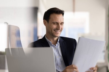 Terfi bildirimi, profesyonel başarılar ve iyi iş haberleri. Belgeleri elinde tutan işadamı, iyi performans ölçümleri, satış artışı veya gelirle mali raporu gözden geçiriyor