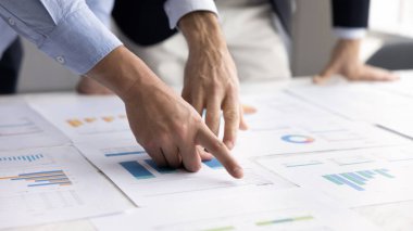 Veri analizi, işbirliği ve stratejik planlama. Bilgi incelemesi, performans değerlendirmesi veya verilen kararlar sırasında tabloya yayılmış grafiklere ve grafiklere işaret eden ellere yakınlaş