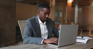 Başarılı Afrikalı Amerikalı iş adamı işini bitirdiği gün projesini tamamlıyor, bilgisayarı kapatıyor, ellerini kestiriyor, sandalyeye yaslanıyor, dişlek gülümsemesiyle dinleniyor.