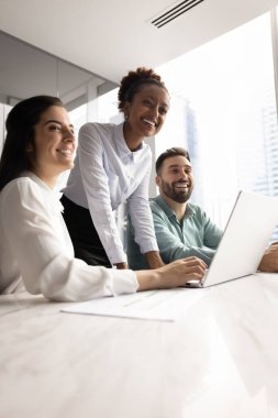 Bir grup mutlu profesyonel ofiste işbirliği yapıyor, konferans masasında belgeler ve dizüstü bilgisayarlarla toplanıyor, gülümsüyor, başka tarafa bakıyor. Takım çalışması, yenilik ve dijital verimlilik, dikey çekim