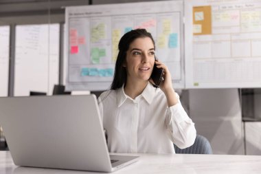 Bilgisayarla masada oturan müşterilerle veya müşterilerle konuşan odaklanmış iş kadını, profesyonel danışma, yardım veya hizmetler sunmaktadır. Telefon, dijital iletişim.
