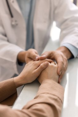 Genç doktor kadın hastanın elini tutuyor, psikolojik ve tıbbi destek veriyor, rahat ettiriyor, zor teşhisi açıklıyor, kötü sağlık sorunlarını anlatıyor. Dikey kırpılmış atış