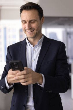 İşadamı akıllı telefon kullanarak iş e-postalarına bakar ve cevap verir, müşteriyi arar, uygulamayla iş arkadaşınızla mesajlaşır, yeni yapay zeka platformu kullanır, gülümser, modern cihaz kullanımından tatmin olur.