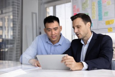 İki erkek konferans masasında oturan tablet ekrana bakıyor, sunumu gözden geçiriyor, slaytları kontrol ediyor veya toplantıya hazırlanıyor, raporları analiz ediyor, mali, pazarlama veya performans verilerini inceliyor