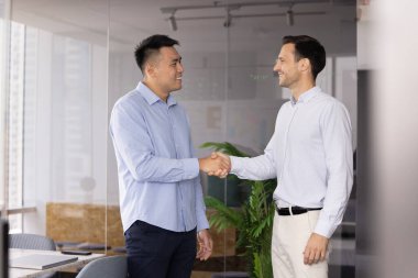 İki iş adamı, modern yönetim kurulunda, olumlu profesyonel etkileşim içinde el sıkışarak modern ofiste işbirliği yapmaya başladılar. Anlaşma, selamlama, ortaklık veya iş anlaşması