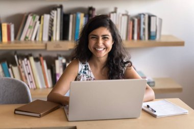 Mutlu iş kadını portresi, dizüstü bilgisayarda çalışan üretken ofis çalışanı, neşeli bir ifadeyle kameraya bakan, görev tamamlanmasından, kariyer büyümesinden ve yeni bilgilerden tatmin olan