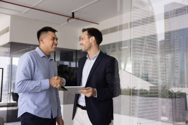 İki mutlu iş adamı, müvekkil ve yönetici el sıkışarak modern yüksek binaların ofisinde karşılıklı saygı göstererek resmi toplantı veya müzakereleri sonuçlandırıyorlar. Anlaşma yapmak, anlaşmayı sonuçlandırmak