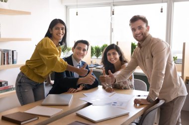 Çeşitli iş adamları toplantı odasında toplandı, kameraya poz verdiler, neşeli bir ifadeyle başparmak gösterdiler, takım çalışması, başarı, başarıyı kutlamak, işbirliği ile tatmin olmak.