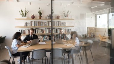 Modern konferans odasında iki çok ırklı iş arkadaşı ortak iş meselelerini çözüyor, dizüstü bilgisayarlarla ve kağıtlarla masada oturuyor, resmi konuşmalara öncülük ediyor, çözümü paylaşıyor ve strateji geliştiriyor.