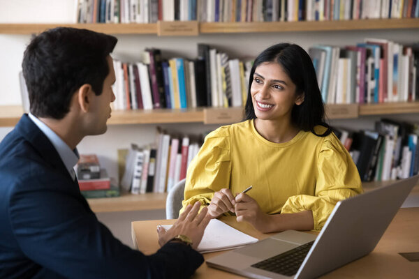 Formal meeting between young Indian woman and Hispanic male colleague, met in office for joint business discussion, new project consideration, reviewing ideas for startup or planning upcoming tasks