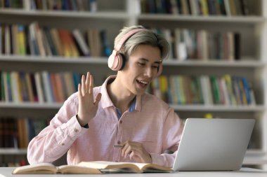 Sanal sınıf katılımı. Uzaktan öğrenim gören gülümseyen gen z çocuk kulaklık takıyor, bilgisayardan ekrana merhaba diyor ve online konferansın başında profesör grup arkadaşlarıyla tanışıyor.