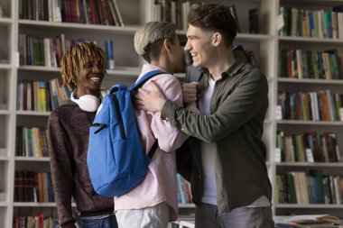 Akademik kardeşlik ve öğrenme başarısı. İki farklı genç öğrenci grup arkadaşı neşeli bir şekilde destekleyici bir şekilde el sıkışırken sınıfta kahkahalar atarak sınav sonrası mezunlar toplantısını kutluyorlar.