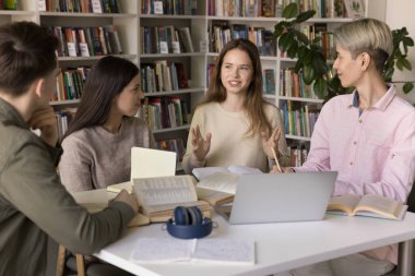 İşbirlikçi eğitim. Kendine güvenen genç liseli kız öğrenci kampüs kütüphanesindeki grup çalışmasında konuşuyor. Çeşitli grup arkadaşlarıyla fikir paylaşımı sorunları çözmek için aktifleştirmeye çalışıyorlar.