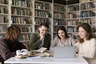 İşbirlikçi dijital çalışma. Çeşitli etnik çeşitlilikte gülümseyen öğrenciler, harmanlanmış öğrenim için dizüstü bilgisayar kullanırlar. Çevrimiçi araştırma araçlarını incelerler. Akademik kaynaklar video sınıfı derslerini grupta izlerler.