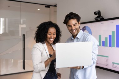 Çeşitli takımlarda ortak başarı. Konferans odasında ayakta duran iki mutlu genç iş adamı ellerinde not defteri olan sunumu hazırlıyorlar. İş planlama istatistik verileri ekranda.