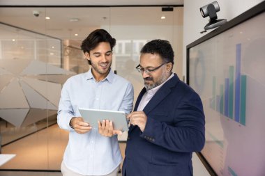 İş ilerlemesi tartışması. Mutlu genç şirket çalışanı proje yöneticisi başarılı çözümü tablet ekranda gülümseyen erkek lider CEO 'ya açıkla.