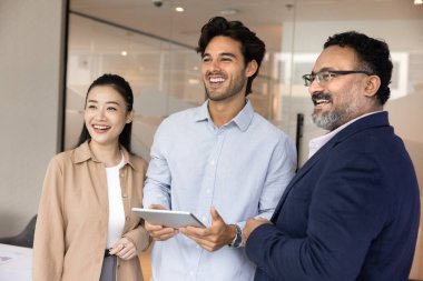 Stratejik vizyon ve olumlu sonuç. Çok ırklı bir grup başarılı bir şekilde gülümsüyor çeşitli iş ortakları bir arada duruyorlar iş yerinde tablet kullanıyorlar, kenara bakın yaratıcı çözümler geliştirin kazanma stratejisi geliştirin