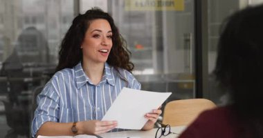 Müzakereler, iş görüşmesi veya resmi görüşme sırasında müşteri veya başvuru yapan genç iş kadını, masada oturuyor, özgeçmişi tutuyor veya sözleşmesi var, yasal kağıt koşullarını tartışıyor