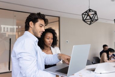 Takım ortamında bilgi paylaşımı. Akıllı genç adam akıl hocası danışmanlık modern açık uzay ofisinde kadın stajyer öğretmek iş görevleri açıklamak notlar ekran üzerinde pazar araştırma sonuçları