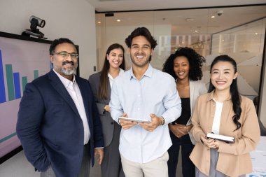 Şirket takım başarısı. 5 farklı çok kültürlü iş adamından oluşan bir grup. Şirketin iş gücü genç çalışanlar ve ofiste fotoğraf çektirmek için poz veren olgun bir lider kameraya bakıp gülümsüyor.