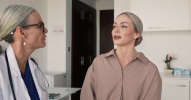 Kadın hasta deneyimli, yetenekli kadın doktorla konuşuyor, hastalık belirtilerini tanımlıyor, endişelerini dile getiriyor, sorular veya tavsiyeler soruyor, klinik ziyareti sırasında profesyonel tıbbi yardım alıyor.