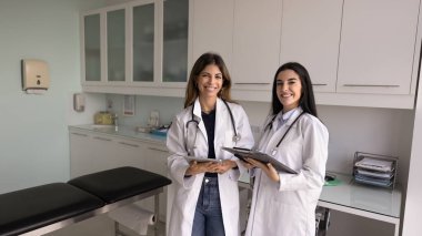 Laboratuvar önlüklü iki başarılı Latin doktor takım çalışması, profesyonel danışma, destek, fotoğraf çekimi için gülümseyen kamera önünde bir araya geliyorlar. Sancak vuruşu