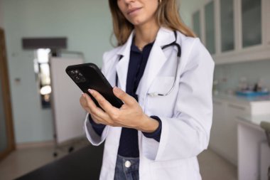 Genç doktor kadının tıbbi web sitesi kullanırken, cep telefonunda teletıp uygulaması kullanırken, hastayla sohbet ederken görüntüsü tanınmaz hale geldi. Tıbbî profesyonel el kameralarını kapatın.