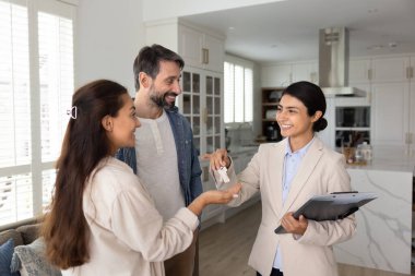 Gülümseyen Hintli kadın, emlakçı evli çiftlere anahtarları veriyor. Ajansın profesyonel hizmetlerinden yararlanarak yeni bir ev bulma deneyimi. Mutlu ev sahipleri, yeni başlangıçlar