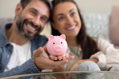 Sevgi dolu evliliklere yakın bir çift pembe kumbarayı ellerinde tutarak yakın otururlar. Birliğin sembolü olarak para kutusu, paylaşılan sorumluluk, tasarruf çabaları, birlikte mali planlama