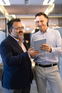 Hintli kıdemli iş adamı, genç beyaz meslektaşından teknik destek istedi ve tablet üzerinde çalışmak için yeni başvuruda bulundu. İnternet içeriğini izleyen çeşitli meslektaşlar. Dikey çekim