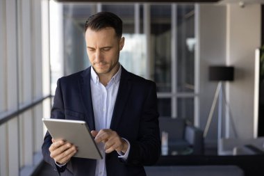 Finans yönetimi uygulamasını kullanan meşgul Latin yönetici, iş iletişimi için tablet bilgisayarda ticaret hizmeti, dijital cihazda daktilo, ofis lobisinde durmak