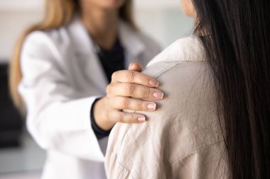 Kadın doktor umut veriyor, destek oluyor, hastayı sakinleştiriyor. Ciddi bir hastalığı olan bir kadının omzuna dokunan, tedavi için motive edici bir doktorun destek eli. Yakın çekim kesilmiş.