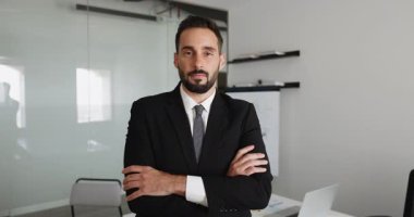 Resmi kıyafetler içindeki kendine güvenen genç Latin şirket CEO 'su. Elleri göğsünde katlanmış bir şekilde portre için poz veriyor. Kameraya bakıyor, olumlu, mutlu, gülümsüyor. İşletme yöneticisi kafasından vuruldu