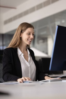 Mutlu, genç, başarılı, 20 'li yaşlarda bilgisayar başında çalışan, büyük bir masaüstü monitörü kullanan, daktilo kullanan, internette gezinen, profesyonel uygulama kullanan, gülümseyen bir kadın. Dikey çekim