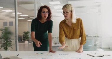 İki profesyonel iş kadını, proje yöneticilerinin el sıkışması hedef dizilimi, strateji geliştirme ve görsel veri yorumlaması, toplantı odasında resmi toplantının başarıyla sonuçlanması.